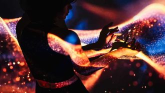 Woman’s hands in dark and projection of abstract light waves on them.