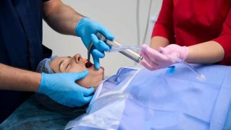 Experienced specialist performs intubation works in the operating room, the patient lies on the operating table