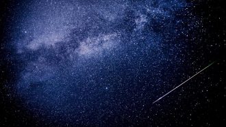 A meteor shoots across the night sky sky leaving a trail of light across the milky way