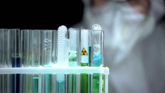 Lab scientist looking at test tubes with radioactive sample ecological pollution