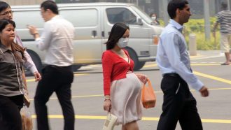 This photo taken on June 20, 2013 shows a pregnant woman with a face mask walking on the street in Singapore.  Singapore's smog index hit the critical 400 level on June 21, making it potentially life-threatening to the ill and elderly people, according to a government monitoring site.  AFP PHOTO/Roslan Rahman        (Photo credit should read ROSLAN RAHMAN/AFP via Getty Images)